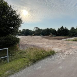 Blick von der Straße auf die Baustelle. Schotter für Parkplatz ist aufgebracht. Hier wird bald unser Neubau stehen