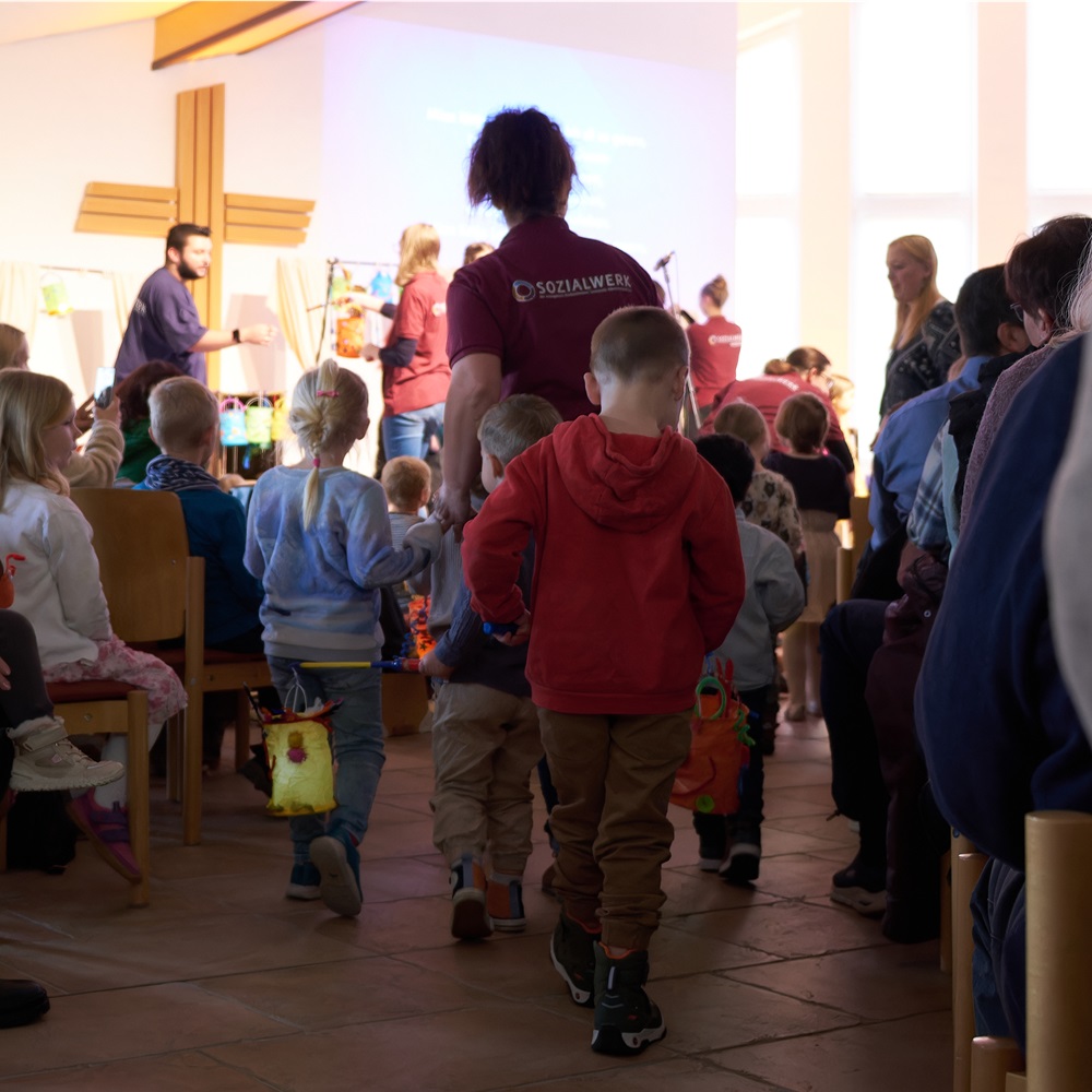 Kinder laufen mit Mitarbeiterin und Laternen auf die Bühne