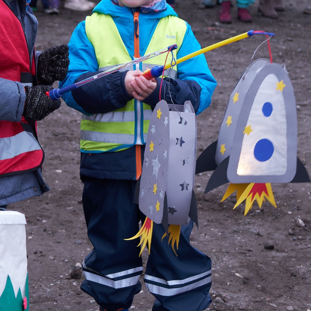 Kinder tragen Raketenlaternen.